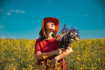 Trendy woman with stylish hat feeling free in the field with flowers