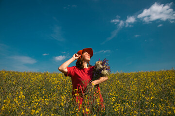 Trendy woman with stylish hat feeling free in the field with flowers