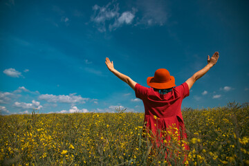Trendy woman with stylish hat feeling free in the field with flowers