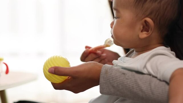 Mother feeding her baby with a spoon.