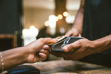 Waiter accepting credit card by contactless payment from customer in cafe