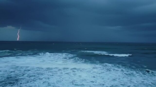 Stormy weather rolls over the ocean waves and beach under a cloudy sky