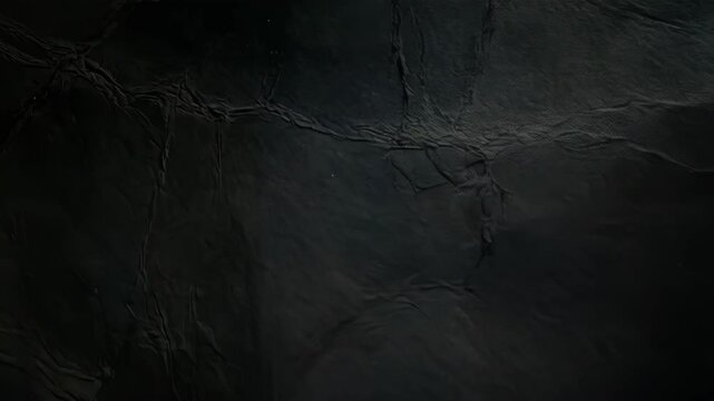 Abstract dark textured paper background featuring creased details and surface variations perfect for artistic projects or design backdrops