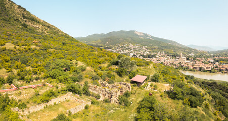 Panoramic aerial view of Armaziskhevi ruins with Mtskheta town, Svetitskhoveli Cathedral, and surrounding Caucasus hills in summer