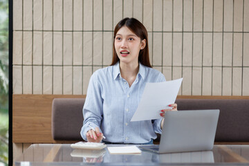  Portrait of young business woman using a calculator to check company finances and earnings and...