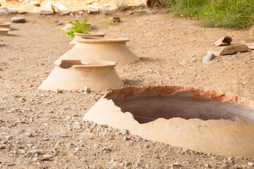 Clay wine vessels embedded in earth beneath wooden shelter at Armaziskhevi site, part of an ancient wine making cellar in Mtskheta region, Georgia
