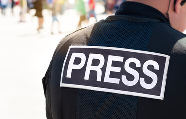 Media press journalist, news reporter, photographer in dangerous field location wearing flak jacket. Journalism covers wars, riots, terrorism and crime for broadcast TV, online websites and print.