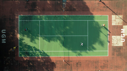 Aerial View of Tennis Players on a Green Court: A Sunny Day Game at UGM