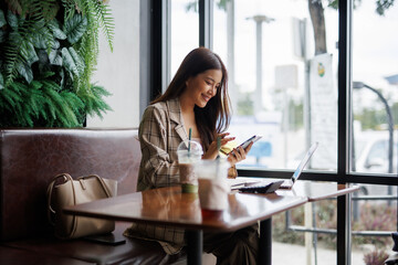 Young asian businesswoman holding credit card and using smartphone for online shopping while sitting in cafe © Crystal