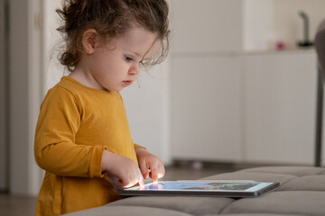 Naklejka premium Child exploring creativity with a drawing app on a tablet in a modern living room environment. 