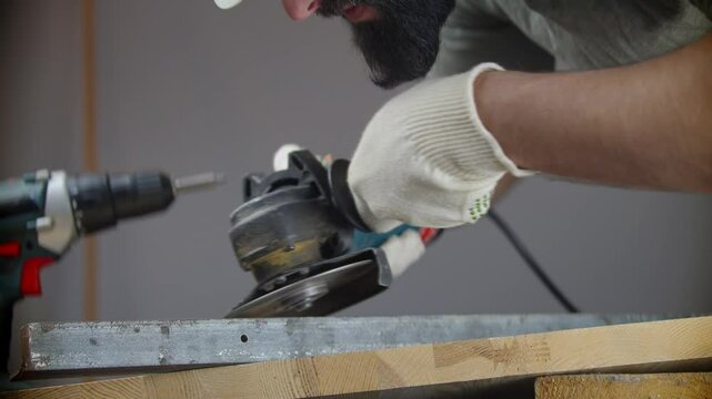 Worker operating power tool while grinding metal surface in workshop	
