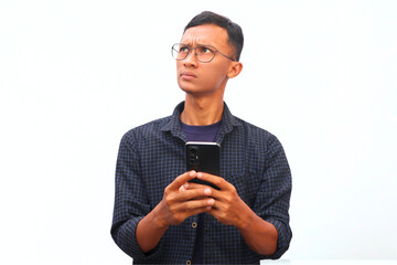 An Asian man holds a cellphone with a thinking expression.