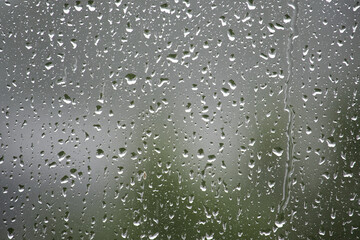 Raindrops on a window create a beautiful, abstract scene with a blurred background.