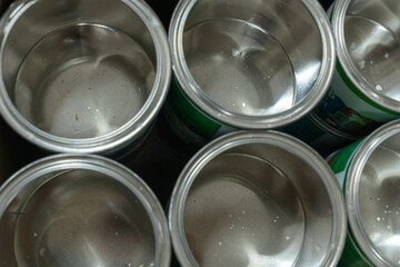 Rows of empty tin cans prepared for vibrant paint production. Empty vessels awaiting paint. Empty tin cans lined up in a paint factory. Rows of empty paint cans in an industrial setting.