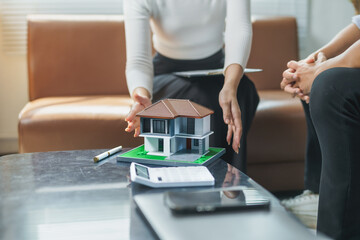 Real estate agent showing house model to client during a meeting, discussing property purchase and investment opportunities