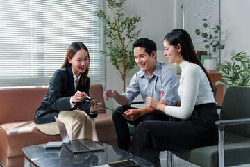 Happy asian realtor pointing at a document with a pen, explaining contract details to a young...
