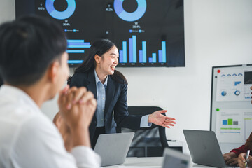 Asian businesswoman leading meeting discussing work with team using laptop computer and digital...