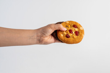 Vanilla cookies topped with nuts and strawberries and A large chocolate cookie topped with chocolate chips on a white background
