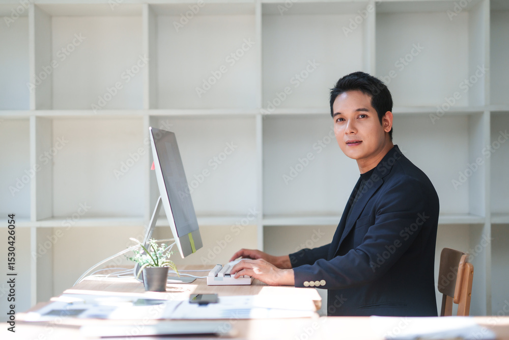 Poster young manager typing on a keyboard and engaging with a desktop computer while working in a modern of