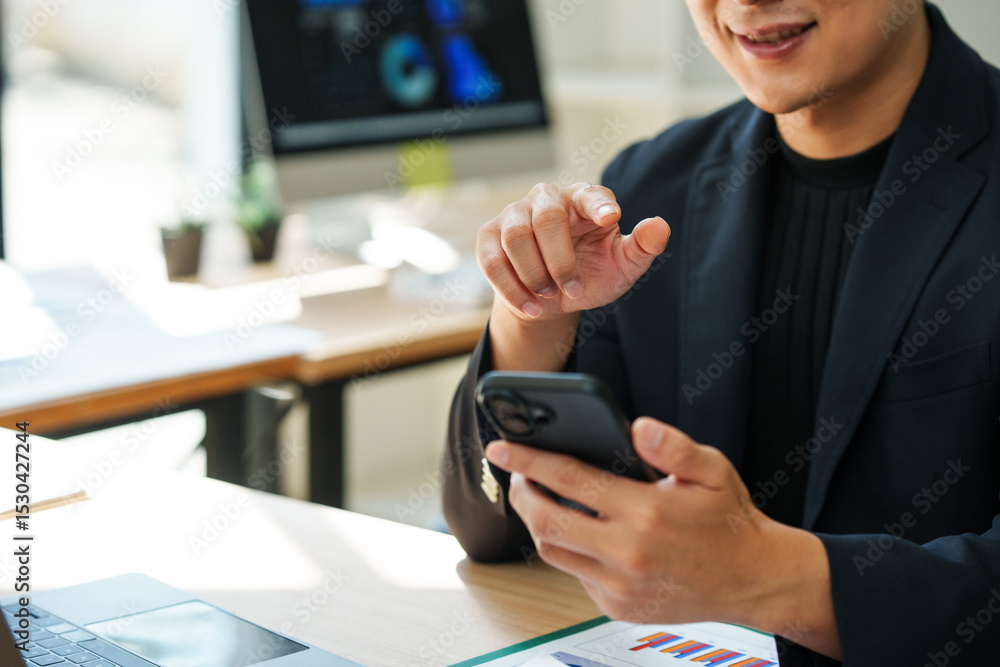 Aufkleber asian businessman browsing on mobile phone and pointing on screen while working at desk in modern of