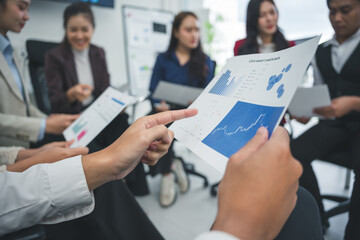 Business colleagues reviewing positive growth charts and graphs, pointing at increasing trend line, discussing financial data in office meeting