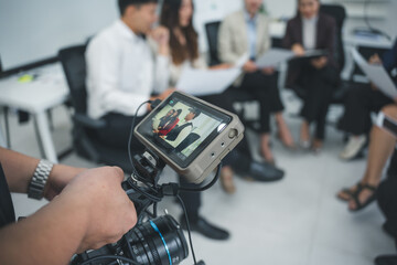 Videographer holding a professional camera, capturing a business meeting in a sleek, modern office...