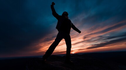 Silhouette of a person celebrating on a mountaintop at sunset.