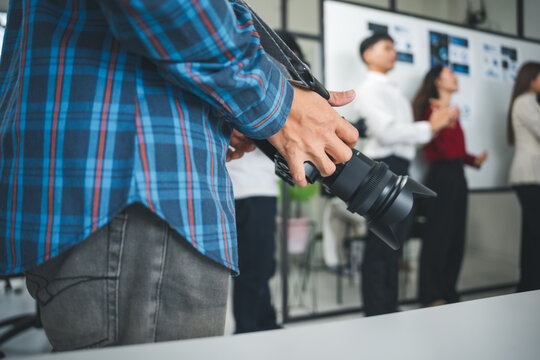 Photographer preparing to capture moments of a business team meeting in a modern office, focusing on collaboration and teamwork