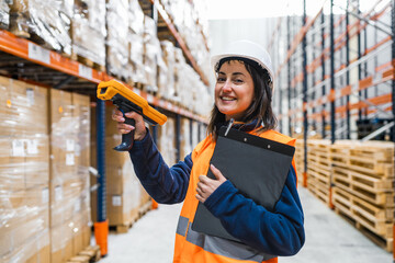 Smiling warehouse worker scanning packages with a barcode scanner while efficiently managing inventory in a busy logistics center