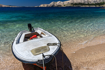 Jablanova Beach, orange fishing boat pulled up on the shore of an empty beach against the backdrop of the Adriatic Sea