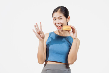 A confident young Asian woman in a sleeveless blue shirt stands against a white background, happily...