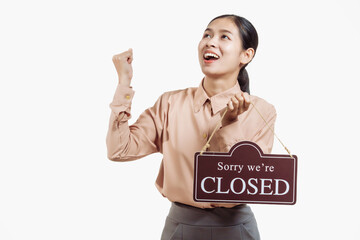 A confident young Asian woman in a light brown shirt stands against a white background, holding a...