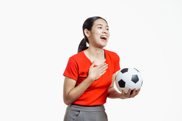 Confident young Asian woman in vibrant red shirt stands against white background, cheering joyfully...