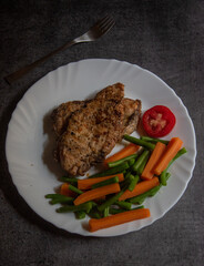 Chicken breast grilled and served with saute vegetables on a plate. Top view, selective focus. 