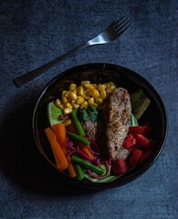 Grilled chicken breast and vegetables in a bowl. Top view.