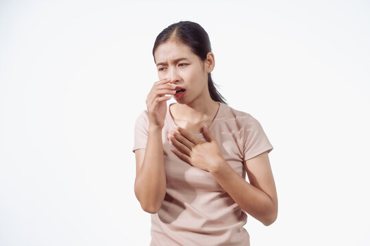 Confident young Asian woman in light brown shirt stands against white background, chest pain. Possible causes include heart, breast, lung, digestive, or musculoskeletal, requiring careful assessment.