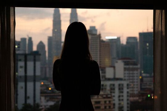 Silhouette of woman at sunset with city skyline - Powered by Adobe