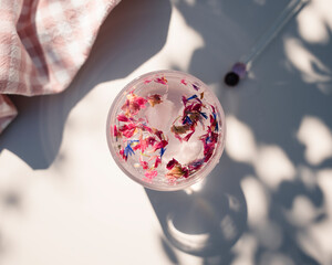 pink drink with fresh edible flowers in it on a table outdoors