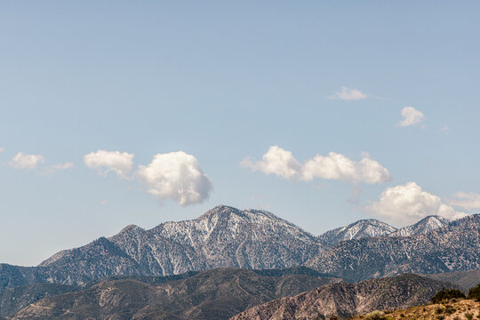 San Gabriel mountains snow capped with puffy clouds
