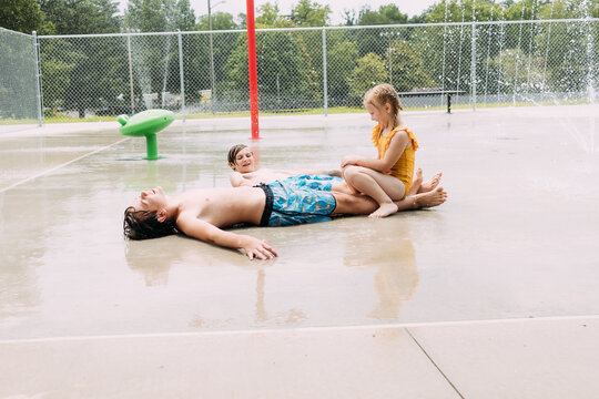Kids playing together at city splash pad on hot summer day