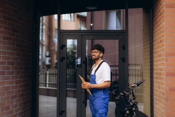 Delivery man holding package leaving building with electric scooter