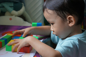 Focused Child Playing with Blocks: A captivating image of a young child engrossed in creative play, carefully arranging colorful blocks, demonstrating focus and early developmental skills.