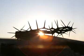 Crown of thorns and red sunset silhouette symbolizing the sacrifice and suffering of Jesus Christ on the cross, Holy Week and Lent background
