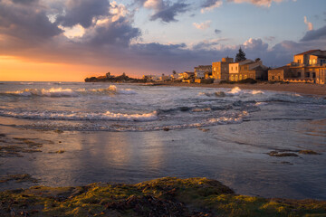 Golden Dusk Casts Its Glow Over Punta Secca's Serene Shoreline in Sicily, Italy