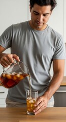 Man Pouring Refreshing Iced Tea Drink Into Glass with Ice at Home