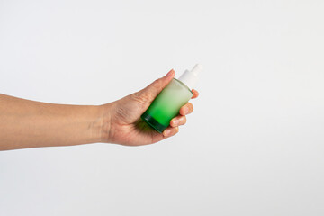 Green glass cosmetic bottle, Skin care or sunscreen cosmetic with hand on white background.
