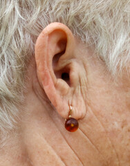 A woman with a gold earring with a brown stone in it