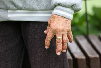 A woman with a ring on her finger is standing in front of a bench