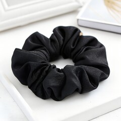 A black scrunchie on a white surface close up 