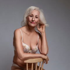 Natural Portrait of Tranquil Sensual Positive Mature Caucasian Woman in White Lingerie Posing With...